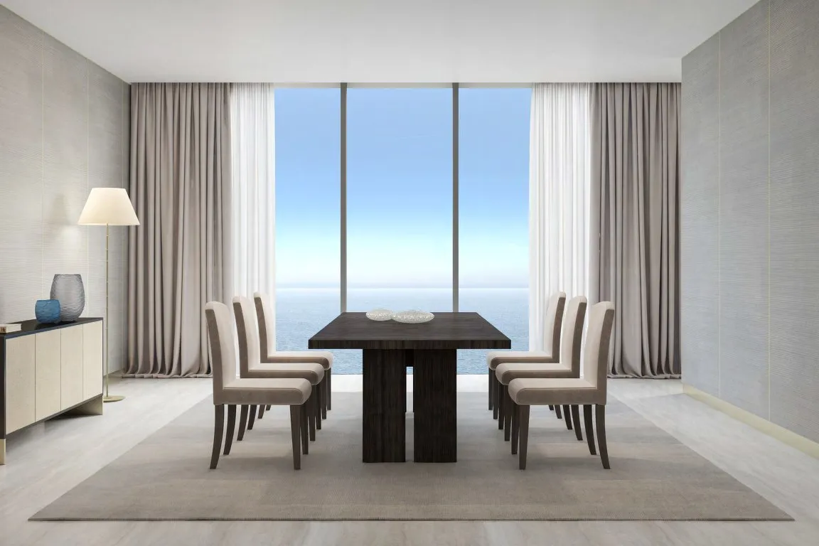 Dining table for eight in front of floor-to-ceiling windows onto the sea