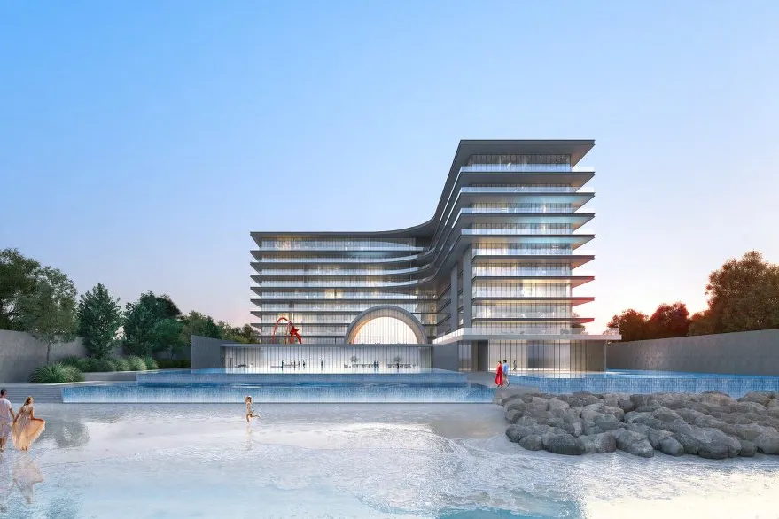 Beach, shallow water and infinity pools in front of the building at dusk